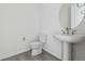 Modern powder room with a pedestal sink, round mirror, updated fixtures, and a white toilet at 25234 E Warren Pl, Aurora, CO 80018