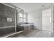 Modern bathroom featuring a glass enclosed shower, soaking tub, and stylish gray tile at 25234 E Warren Pl, Aurora, CO 80018