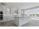 A spacious, light-filled kitchen featuring a large center island, white cabinetry, and stainless steel appliances at 25234 E Warren Pl, Aurora, CO 80018