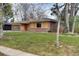 Home featuring a green garage door, wood paneling, and a well manicured lawn at 404 S Oneida Way, Denver, CO 80224