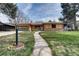Lovely home featuring a stone walkway, green lawn, mature trees and wood and brick accents at 404 S Oneida Way, Denver, CO 80224