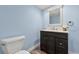 Bathroom featuring light blue walls, a toilet, and a vanity with a dark brown cabinet and a decorative mirror at 1104 Fieldstone Pl, Highlands Ranch, CO 80126