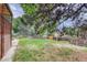 Spacious backyard with mature trees, a wooden fence, and lush green grass at 2621 S Kingston Ct, Aurora, CO 80014