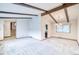 An open-concept living room with exposed wood beam, neutral carpeting, and dining area with chandelier at 2621 S Kingston Ct, Aurora, CO 80014