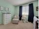 This well-appointed Bedroom is furnished with a white dresser, comfortable chair, and charming decor at 7557 S Cove Cir, Centennial, CO 80122