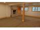 Spacious basement area featuring a stone fireplace, carpet floors, and natural lighting through the windows at 5237 S Olive Rd, Evergreen, CO 80439