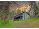 Charming two-story home with a spacious deck on a green hillside surrounded by mature trees at sunset at 5237 S Olive Rd, Evergreen, CO 80439