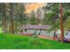 Charming single-story home featuring a wooden deck and is surrounded by a lush green lawn and mature trees at 5237 S Olive Rd, Evergreen, CO 80439
