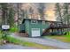 Charming two-story green home with a deck and garage surrounded by trees with a camper and stone at 5237 S Olive Rd, Evergreen, CO 80439