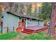 Back exterior view of the home featuring a deck, trees, and natural lighting at 5237 S Olive Rd, Evergreen, CO 80439
