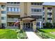 Inviting condo building showcasing professional landscaping, flags, and a covered entryway at 695 S Alton Way # 5A, Denver, CO 80247