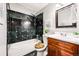 Bathroom features a tub, shower, and vanity with sleek black and white decor at 5202 Dillon St, Denver, CO 80239