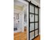 Hallway with glass-paned barn door, hardwood floors, and views into bedroom and bathroom at 1445 Elm St, Denver, CO 80220