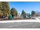 Outdoor playground area for the complex featuring snowy ground, tall trees and plenty of equipment at 3663 S Sheridan Blvd # 2, Denver, CO 80235