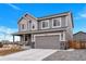 Gray two-story home featuring a two-car garage, covered front porch, and well-maintained landscaping at 5253 Cherry Blossom Dr, Brighton, CO 80601