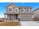 Charming two-story home with gray siding, a covered front porch, and an attached two-car garage at 5253 Cherry Blossom Dr, Brighton, CO 80601