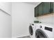 Functional laundry room with modern washer and dryer units, featuring stylish overhead cabinets at 5253 Cherry Blossom Dr, Brighton, CO 80601