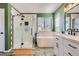 Modern bathroom featuring hexagon tile, sleek fixtures, and a freestanding tub under a window at 2649 Westgate Ave, Highlands Ranch, CO 80126