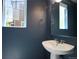 Powder room featuring sleek pedestal sink, dark blue walls, and a window offering natural light at 3429 Hardin St, Castle Rock, CO 80109