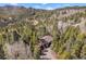 Aerial view of a mountain home surrounded by dense forest, showing its elevated deck and vehicle at 11557 Green Cir, Conifer, CO 80433