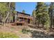 Two-story mountain house featuring spacious wooden decks on both levels, nestled among lush trees at 11557 Green Cir, Conifer, CO 80433