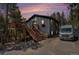 Charming dark gray home showcasing a deck, natural wood stairs and surrounding trees at 11557 Green Cir, Conifer, CO 80433