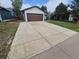 A long concrete driveway leads up to an attached garage on this suburban home at 3735 S Lewiston St, Aurora, CO 80013