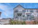 Modern two-story townhome with gray and white exterior, landscaped yard, and black metal fence at 9275 Merino Ct # A, Littleton, CO 80125