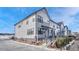 Modern townhome with gray and white exterior, landscaped yard, and black metal fence. Additional homes are visible at 9275 Merino Ct # A, Littleton, CO 80125