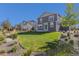 Landscaped backyard featuring a well-kept lawn, patio, and attractive stone borders with planted trees at 1953 Morgan Dr, Erie, CO 80516