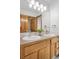 Well-lit bathroom featuring double sinks, wood cabinetry, and a large mirror at 13516 Thorncreek Cir, Thornton, CO 80241