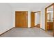 Bedroom with multiple doors, wood trim and carpeted floor leading to the bathroom at 13516 Thorncreek Cir, Thornton, CO 80241