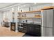 Stylish bar area with dark cabinetry, granite countertops, stainless steel appliances, and open shelving at 8833 Portico Ln, Longmont, CO 80503