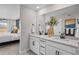 Elegant bathroom featuring double sinks, quartz countertops, and a large mirror and a view into the bedroom at 17112 W 91St Ln, Arvada, CO 80007