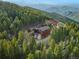 Breathtaking aerial view of a mountain home surrounded by lush forest and majestic mountains at 197 Sawmill Ln, Idaho Springs, CO 80452