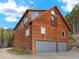 Exterior view of a rustic, wood-clad home with a two-car garage and ample windows at 197 Sawmill Ln, Idaho Springs, CO 80452
