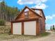 Charming exterior of a two-story home with a two-car garage and beautifully wooded surroundings at 197 Sawmill Ln, Idaho Springs, CO 80452