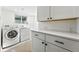 Bright laundry area features white cabinets and modern washer and dryer at 1731 Locust St, Denver, CO 80220