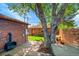 Private brick patio with a modern fireplace, lush tree, and manicured landscape at 2901 Monaco Pkwy, Denver, CO 80207