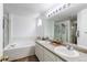 Bright main bathroom featuring double sinks, large mirror, glass shower, and separate tub at 11183 E 114Th Ave, Commerce City, CO 80640