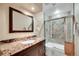 Stylish bathroom featuring a granite countertop, framed mirror, and tiled shower with glass door at 22029 E Irish Dr, Aurora, CO 80016