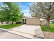 Front view of home with a two-car garage, lush lawn, and mature trees at 8240 Clayton Ct, Denver, CO 80229