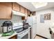 This galley kitchen features wood cabinetry, white appliances, and a bright overhead skylight at 2201 Sable Blvd # 1003, Aurora, CO 80011