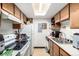Galley kitchen features wooden cabinets, white appliances, and a bright skylight overhead at 2201 Sable Blvd # 1003, Aurora, CO 80011