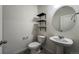 This bathroom features a pedestal sink, oval mirror and black shelving for a contemporary look at 2325 Mountain Sky Dr, Fort Lupton, CO 80621