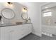 This bathroom offers a dual vanity with shiplap accents and elegant lighting, adjacent to a tiled shower and tub area at 3256 S Corona, Englewood, CO 80113