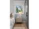 Bright bedroom featuring a wood floor, stylish nightstand, and comfortable white bedding, with view to a green outdoor scenery at 3256 S Corona, Englewood, CO 80113