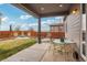 Covered patio with outdoor dining set and views of the backyard fire pit at 13960 Box Turtle Loop, Parker, CO 80134