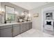 Bathroom featuring a double vanity with gray cabinets, modern fixtures, and a herringbone accent wall at 10660 Weathersfield Ct, Highlands Ranch, CO 80129