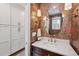 Chic bathroom with an ornate mirror, wood vanity, marble countertop, and stylish floral wallpaper at 10660 Weathersfield Ct, Highlands Ranch, CO 80129